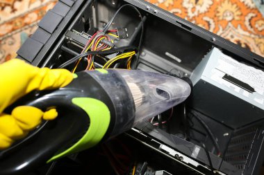 Inside details of the personal computer. Man is cleaning wires with vacuum cleaner. Small hoover. Motherboard and video card in the dust. Broken PC.