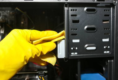 Inside details of the personal computer. Man is cleaning wires in yellow gloves. Motherboard and video card in the dust. Broken PC.