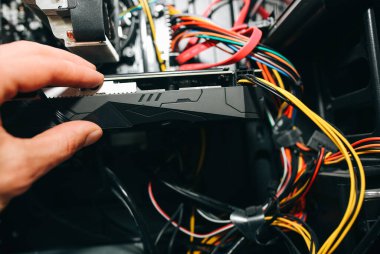 Kişisel bilgisayarın içinde. Adam sarı eldivenlerle kabloları temizliyor. Anakart ve video kartı toz içinde. Kırık PC.