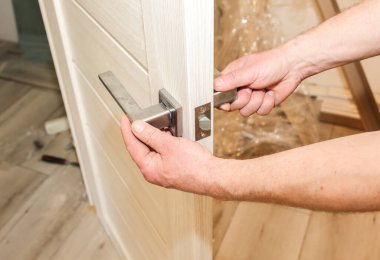 Adam kapı kolunu kuruyor. Onarım işe yarıyor. Dairede bakım var..