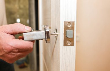 Adam kapı kolunu kuruyor. Onarım işe yarıyor. Dairede bakım var..