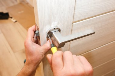 Adam kapı kolunu kuruyor. Onarım işe yarıyor. Dairede bakım var..