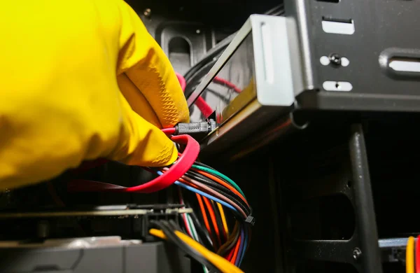 Inside details of the personal computer. Man is cleaning wires in yellow gloves. Motherboard and video card in the dust. Broken PC.