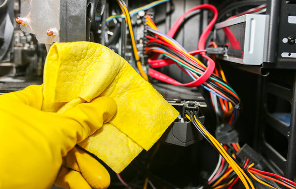 Inside details of the personal computer. Man is cleaning wires in yellow gloves. Motherboard and video card in the dust. Broken PC.