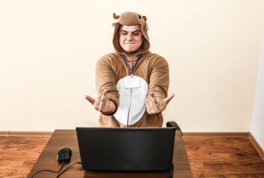 İnek kostümü giymiş bir ofis çalışanı. Laptopun yanında komik hayvan pijamalı adam. Çaresiz yöneticiye parodi. Mesleki tükenme.