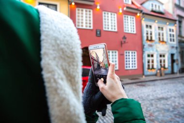 RIGA, LATVIA - DECEMBER 07, 2018: Woman is taking a photo of beautiful street in Riga. Christmas mood and atmosphere. Winter festive time.