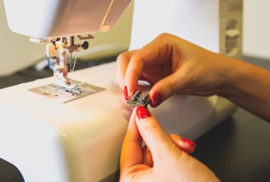 Kadın dikiş makinesine iplik koyuyor. Serbest çalışan kızlar ellerini kullanıyor. Moda konsepti. Yeni kıyafet süreci oluşturuluyor. Hobi fikirleri.