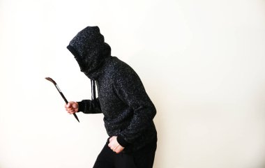 Kapının yanında demir levye olan bir suçlu. Siyah kapüşonlu bir soyguncu..