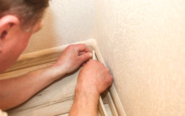 Adam süpürgeliği kuruyor. İçeride tamirat işe yarar. Dairede tadilat var. Elinde mezura var..