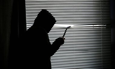 Levyeli bir suçlu pencereden gözetliyor. Eski panjurlar.