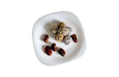 Raw sweets isolated on white background. Figs with candies and sesame on white plate.
