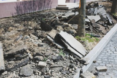Eski kasabada yol çalışır. Yerde taşlar ve kaldırımlar var. Sokaklarda yeniden yapılanma. Kaldırım tamiri. Kırık asfalt.