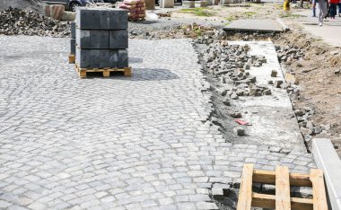 Eski kasabada yol çalışır. Yerde taşlar ve kaldırımlar var. Sokaklarda yeniden yapılanma. Kaldırım tamiri. Somut.