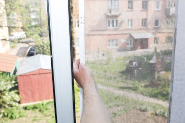 Man is installing the mosquito net on the window. Protection from bugs.