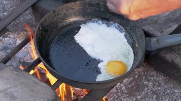 Macho, papas fritas turísticas Huevos fritos sobre una hoguera en una sartén al aire libre. De cerca. — Vídeo de stock