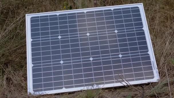 Een draagbaar klein fotovoltaïsch zonnepaneel geïnstalleerd in het gras. Zoom — Stockvideo