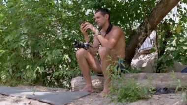 Fotoğrafçı, Smartphone 'la Çadırın Yakınındaki Log' da oturuyor, elinde Kamera var. 4K