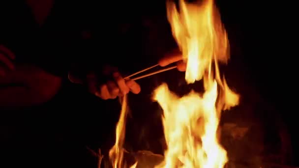 Mužské ruce smažení dva šťavnaté klobásy v noci na ohni venku v lese — Stock video