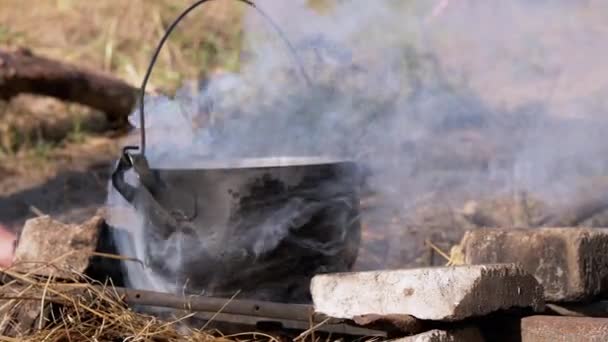 Cucinare il cibo in una casseruola Durante un falò aperto nel fumo al tramonto. 4K. Da vicino. — Video Stock