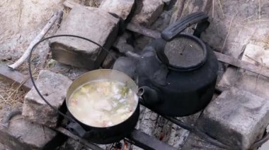 Açık havada, ormanda bir tencerede şenlik ateşinde yemek hazırlıyorum. Yakınlaştır. Kapat.