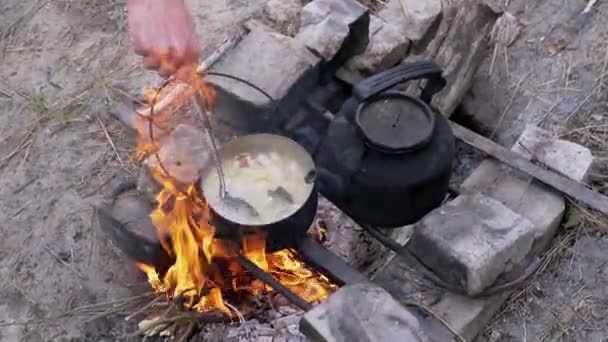 在森林户外篝火上用平底锅准备食物的男性。放大。靠近点 — 图库视频影像