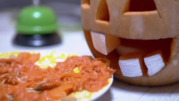 Χαραγμένη κολοκύθα Jack Lantern κεφάλι με ανοιχτό στόμα κοντά σε μια μάζα κολοκύθας πιάτο. Εστίαση — Αρχείο Βίντεο