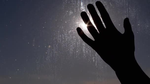 La mano femenina juega con rayos de luz solar sobre un fondo de vidrio húmedo. De cerca. — Vídeo de stock