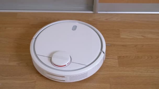 Un moderno aspirapolvere robot automatico spazza i detriti sul pavimento in camera. Da vicino. — Video Stock