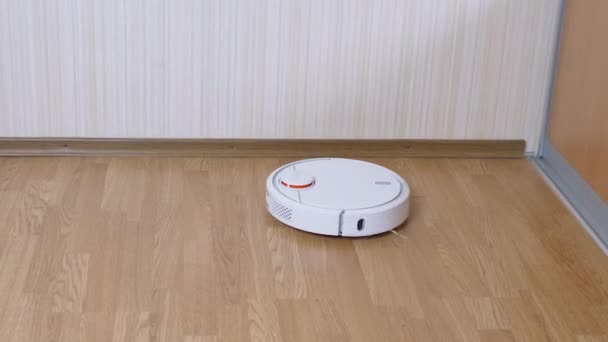 Una aspiradora automática moderna del robot barre los desechos en el piso en la habitación. De cerca. — Vídeo de stock