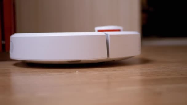 Een moderne automatische robot Stofzuiger veegt puin op de vloer in de kamer. Sluiten. — Stockvideo