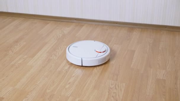 Ένα σύγχρονο αυτόματο ρομπότ ηλεκτρική σκούπα σαρώνει συντρίμμια στο πάτωμα στο δωμάτιο. Κλείσε. — Αρχείο Βίντεο
