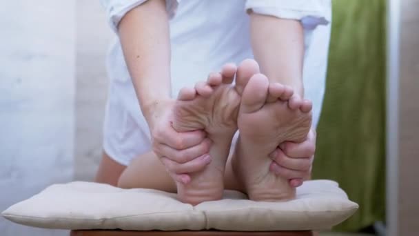 Las manos de un masajista, terapeuta están masajeando los pies desnudos, las plantas de un niño. 4K — Vídeo de stock