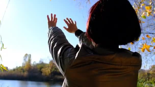 Mujer feliz tira de las manos hacia la luz del sol al aire libre. 4K. De cerca. — Vídeos de Stock