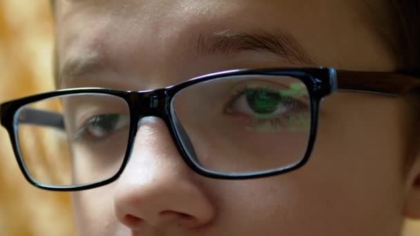 戴眼镜的孩子看电视，放着镜头中的荧幕字幕 — 图库视频影像