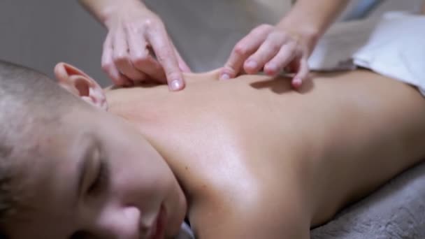 Las manos del masajista están masajeando la espalda de un adolescente, un niño en un salón de spa — Vídeo de stock