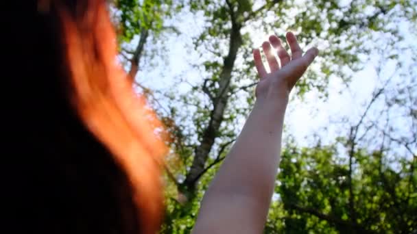幸せな女の子の手は日没時に日光に手を差し伸べます。閉めろ。スローモーション — ストック動画