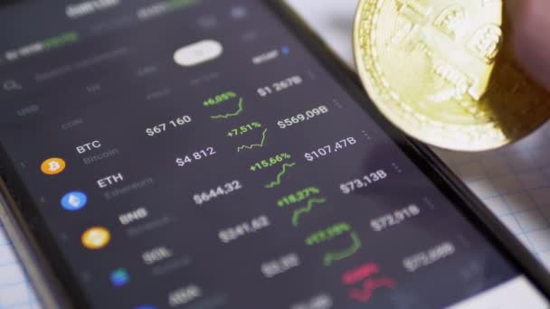 Man roteert Bitcoin Coin Over Smartphone Screen Toont de groei van Cryptocurrency — Stockvideo