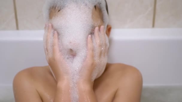 Bagni ragazzo in bagno, Gioca con bolle di schiuma sapone, rende divertenti maschere schiuma — Video Stock