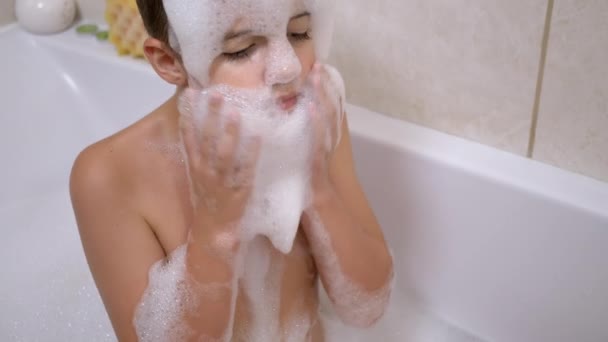 Jongen baden in de badkamer, Spelen met bubbels van zeepachtige schuim, Maakt grappige schuim maskers — Stockvideo