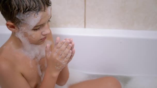 Chłopiec kąpie się w łazience, dmuchanie baniek mydlanych, sprawia, że śmieszne maski piankowe. Zbliżenie — Wideo stockowe