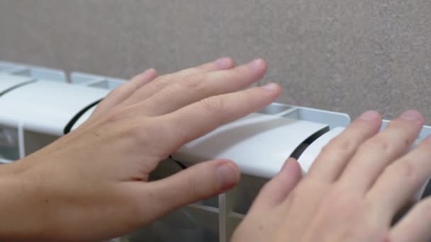 Una femmina riscalda le mani sopra una batteria, un riscaldatore a casa in una stanza. 4K. Rallentatore — Video Stock