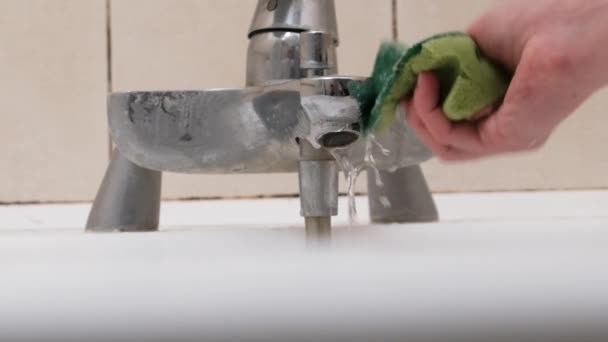 Una mano femenina limpia un grifo sucio con una esponja y detergente en el baño — Vídeo de stock