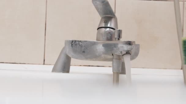 Una mano femenina limpia un grifo sucio con una esponja y detergente en el baño — Vídeo de stock