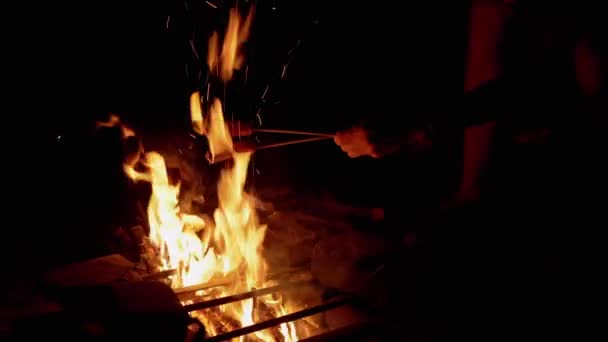 Hombre hambriento freír dos jugosas salchichas en la noche en una hoguera al aire libre en el bosque — Vídeos de Stock