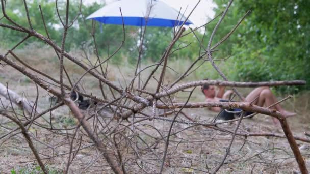 Torra grenar för ved Ligg i naturen mot bakgrund av en vilande turist — Stockvideo