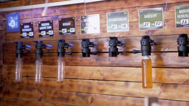 Μπύρα σε πλαστικά μπουκάλια που κρέμονται σε δοχεία μπύρας σε μπαρ στον τοίχο. Κλείσε. 4K — Αρχείο Βίντεο