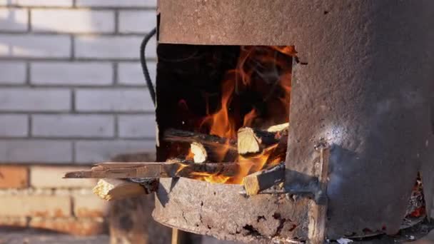 Burning Firewood in an Old Rusty Stove Outdoors in the Rays of Sunlight. 4K — Stockvideo