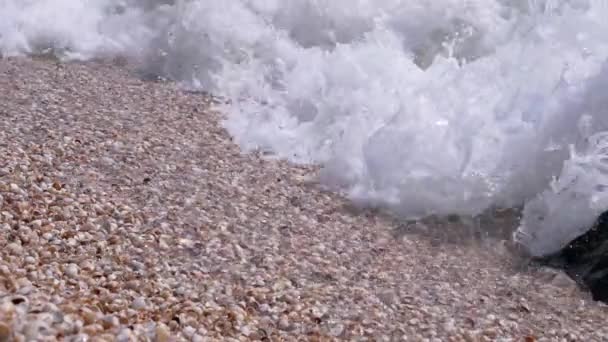 Sea Wave with Foams Rolls onto the Sandy Shore from Shells (en inglés). De cerca. — Vídeo de stock