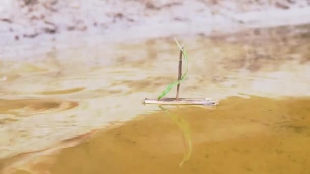 A Child Lowers a Homemade Wooden Ship with a Green Leaf Sailboat in Water. 4K — Stock Video