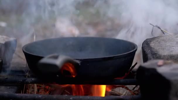 Sartén humeante en una hoguera ardiente en el bosque. De cerca. — Vídeos de Stock